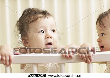 Stock Photography - Twin babies in cot. Fotosearch