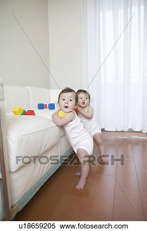 Twin babies leaning on couch View Large Photo Image Stock Photography - Twin babies leaning on couch. Fotosearch