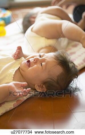 Twin babies lying on floor View Large Photo Image Picture - Twin babies lying on floor. Fotosearch