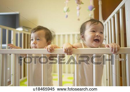 Stock Photography - Twin baby girls in cot. Fotosearch