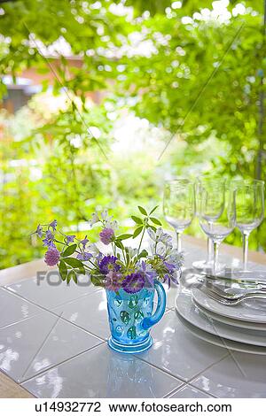 Stock Image - Vase of flowers and tableware on table. Fotosearch