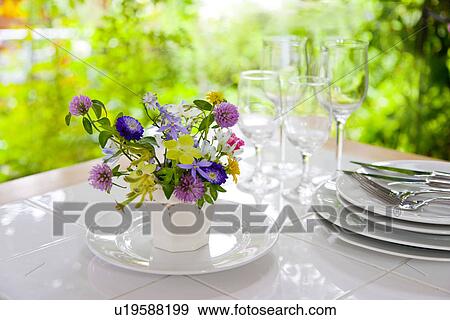 Stock Photo - Vase of flowers and tableware on table. Fotosearch