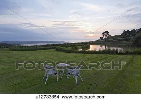 Picture - White Table and Two Chairs in Green Field. Fotosearch