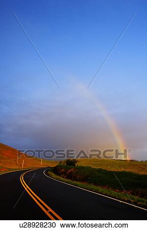 Stock Image - Winding Road and Rainbow in the Sunset Sky, Hawaii, USA. Fotosearch