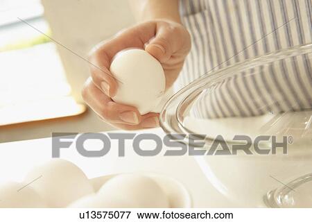Stock Photo - Woman cracking egg, close up. Fotosearch