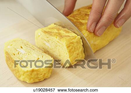 Stock Photo - Woman cutting rolled egg, close up. Fotosearch