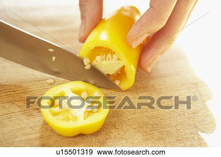 Stock Photo - Woman cutting yellow bell pepper, close up. Fotosearch