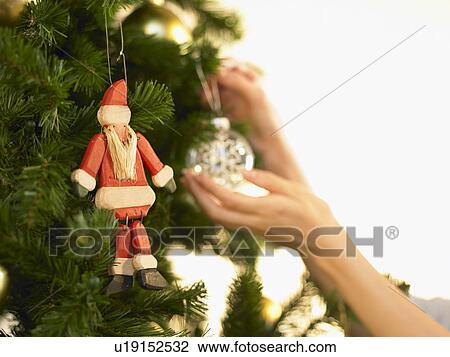 Stock Image - Woman decorating Christmas tree, close up. Fotosearch