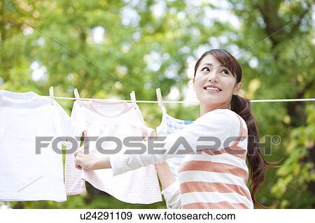 Stock Photo - Woman drying laundry, smiling and looking back. Fotosearch