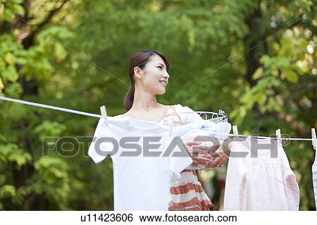 Stock Photograph - Woman drying laundry, smiling and looking away. Fotosearch