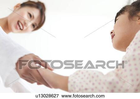 Stock Photo - Woman holding daughter's hands, smiling, white background. Fotosearch