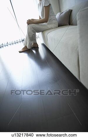 Woman in living room, sitting on sofa View Large Photo Image Stock Image - Woman in living room, sitting on sofa. Fotosearch