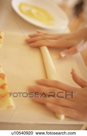 Stock Image - Woman making bagels, rolling dough, close up, blurred motion. Fotosearch