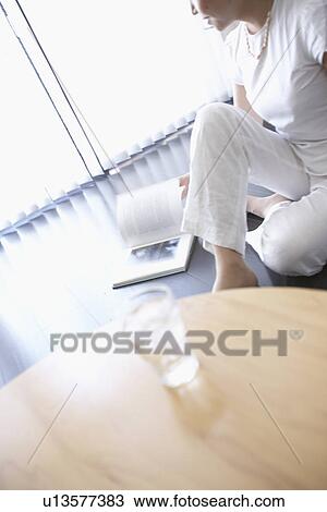 Stock Image - Woman reading book, turning page. Fotosearch