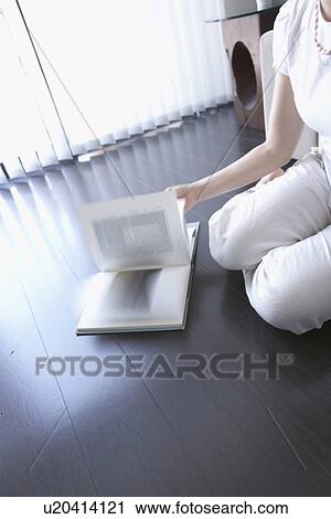 Stock Image - Woman reading book, turning page. Fotosearch