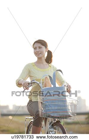 Stock Image - Woman riding bicycle, looking away. Fotosearch