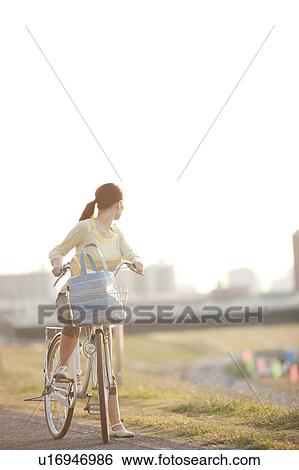 Stock Photograph - Woman riding bicycle, looking back. Fotosearch