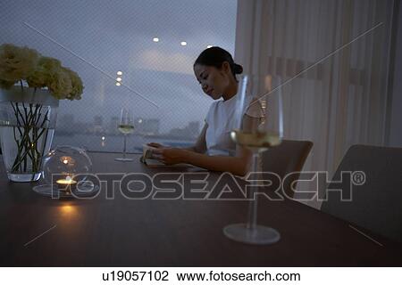 Stock Image - Woman sitting at table, wineglasses on table. Fotosearch