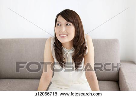 Woman sitting on a sofa View Large Photo Image Stock Photo - Woman sitting on a sofa. Fotosearch