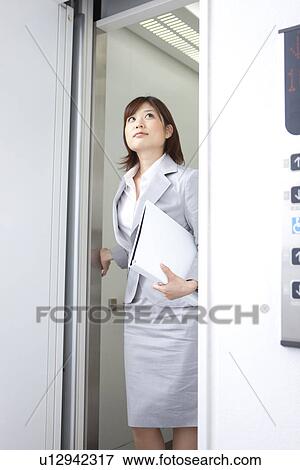 Stock Photo - Young businesswoman exiting elevator. Fotosearch