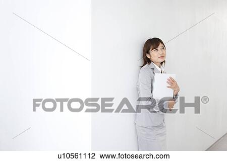 Young businesswoman looking up at corridor, holding binder View Large Photo Image Stock Image - Young businesswoman looking up at corridor, holding binder. Fotosearch