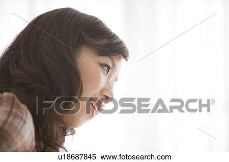 Stock Photography - Young woman by window, smiling, close up. Fotosearch