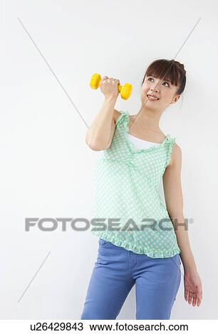 Young woman doing exercise, using dumbbells, white background View Large Photo Image Stock Image - Young woman doing exercise, using dumbbells, white background. Fotosearch