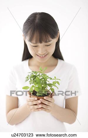 Stock Image - Young Woman Holding Herb Pot. Fotosearch