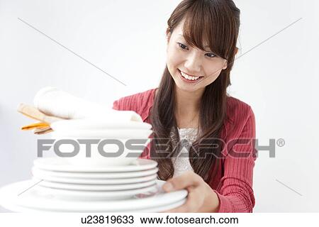 Young woman holding pile of plates, white background View Large Photo Image Stock Image - Young woman holding pile of plates, white background. Fotosearch