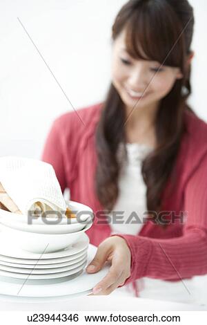 Young woman holding pile of plates, white background View Large Photo Image Stock Photograph - Young woman holding pile of plates, white background. Fotosearch