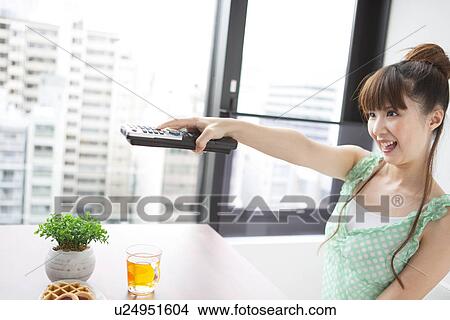 Young woman holding remote control, smiling View Large Photo Image Picture - Young woman holding remote control, smiling. Fotosearch