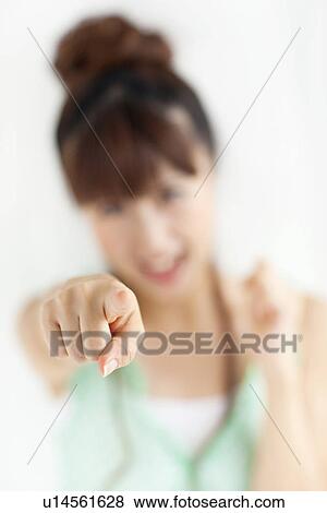 Stock Photo - Young woman pointing forward, white background, differential focus. Fotosearch
