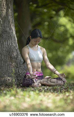 Stock Photograph - Young Woman Practicing Meditation Under Tree. Fotosearch