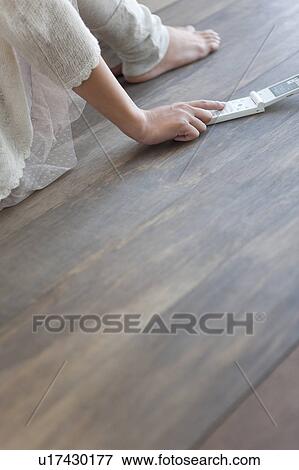 Stock Photo - Young woman sitting on floor, using mobile phone. Fotosearch