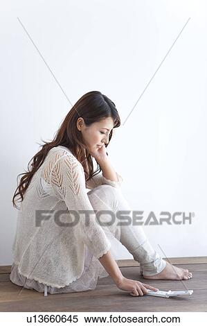 Young woman sitting on floor, using mobile phone, white background View Large Photo Image Stock Photography - Young woman sitting on floor, using mobile phone, white background. Fotosearch
