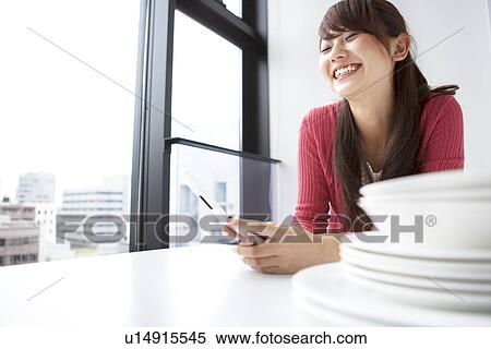 Young woman using mobile phone, smiling View Large Photo Image Stock Photography - Young woman using mobile phone, smiling. Fotosearch