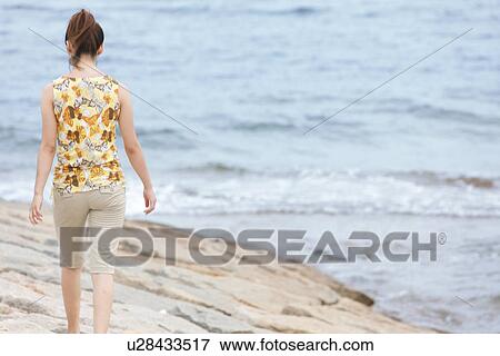 Stock Photo - Young woman walking at beach. Fotosearch