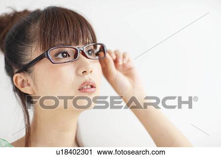 Stock Image - Young woman wearing glasses, white background. Fotosearch