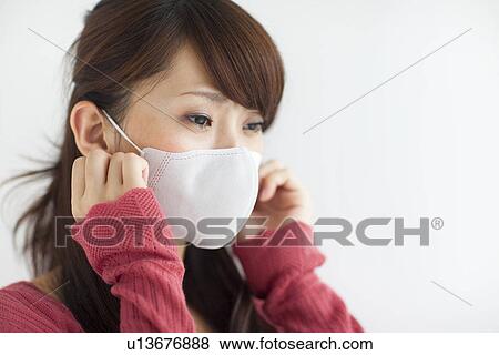 Stock Photo - Young woman wearing mask, white background. Fotosearch