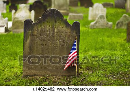 Stock Image - American flag in front of tombstone. Fotosearch
