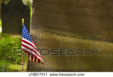 Stock Image - American flag in front of tombstone. Fotosearch