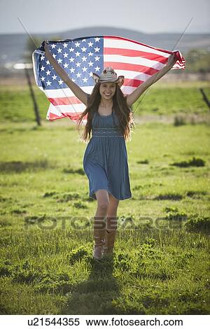 Stock Photography - Beautiful cowgirl running with American flag in her arms. Fotosearch
