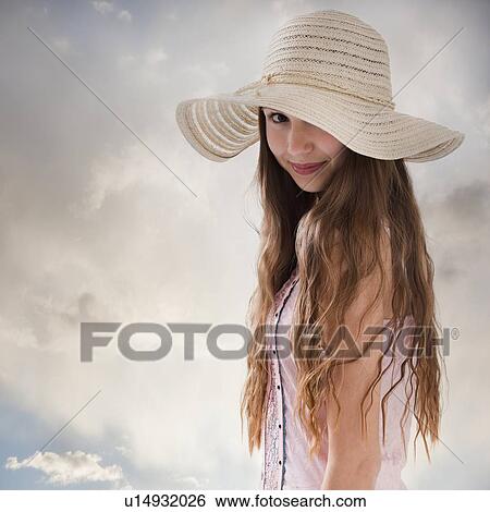 Stock Photograph - Beautiful long haired woman wearing a straw hat. Fotosearch