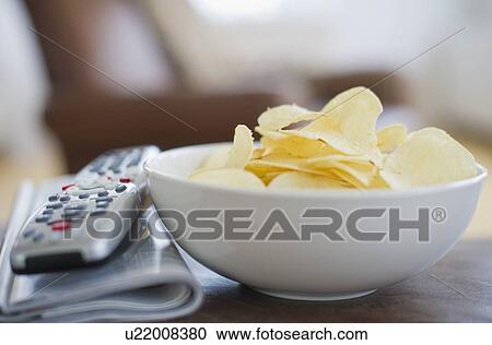 Bowl of chips beside remote control View Large Photo Image Stock Image - Bowl of chips beside remote control. Fotosearch
