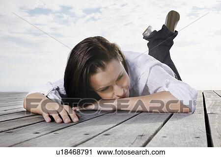 Stock Image - Brunette woman relaxing on porch. Fotosearch