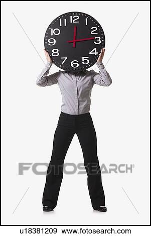 Businesswoman holding clock in front of her face View Large Photo Image Stock Photo - Businesswoman holding clock in front of her face. Fotosearch