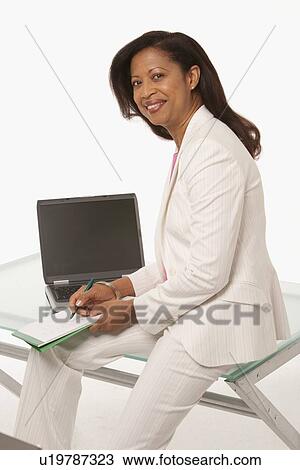 Businesswoman sitting on desk View Large Photo Image Stock Image - Businesswoman sitting on desk. Fotosearch