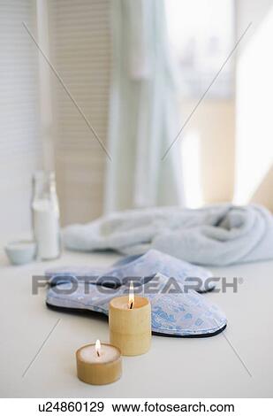 Stock Photo - Candles slippers and robe at spa. Fotosearch