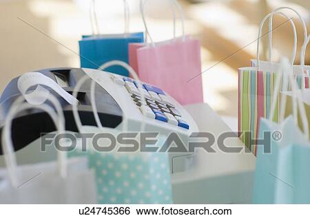 Cash register surrounded by colorful shopping bags View Large Photo Image Stock Photograph - Cash register surrounded by colorful shopping bags. Fotosearch