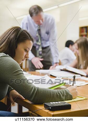Stock Image - College professor helping student in library. Fotosearch
